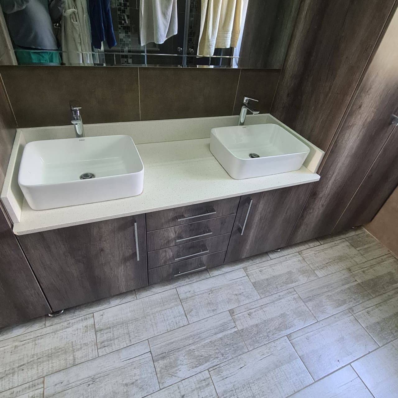 Custom double basin bathroom vanity with dark wood grain cabinets, drawers and a quartz top