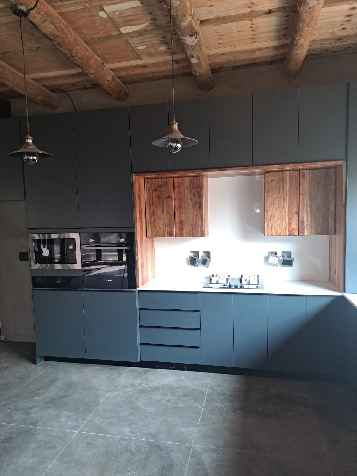Dark matte kitchen with reclaimed wood accents and pendant lighting